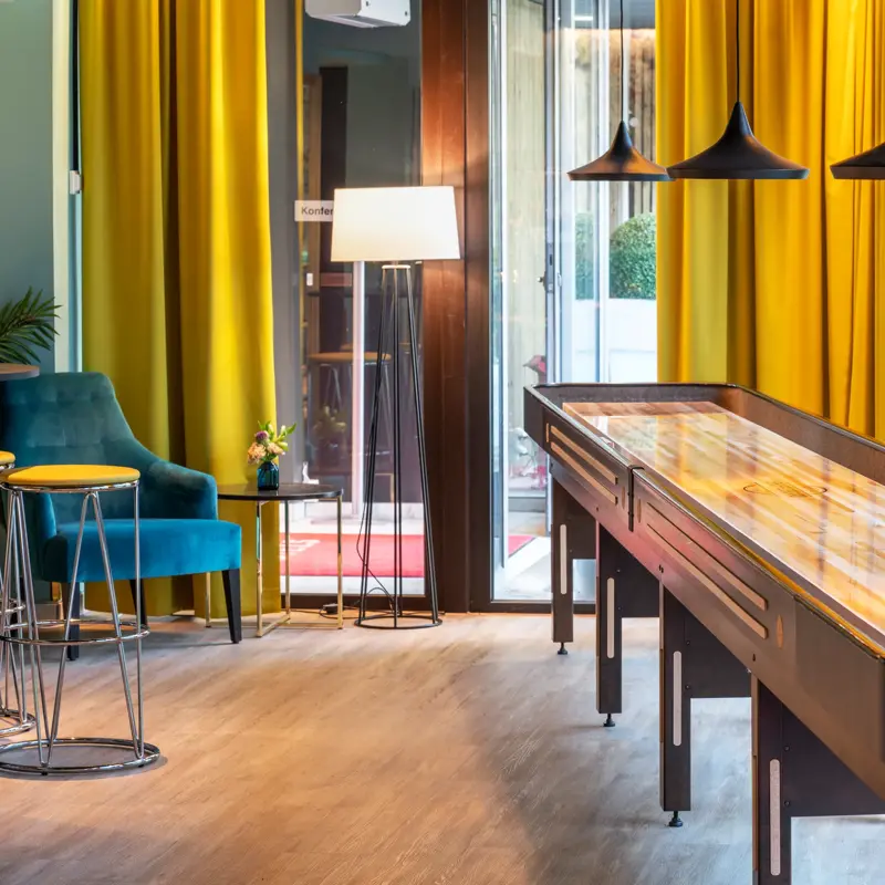 Shuffleboard, store vinduer og gule gardiner i lobbyen på Thon Hotel Maritim