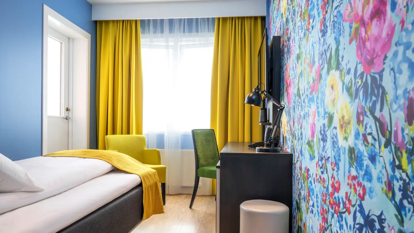 Seng, skrivebord,stol og blomstrete tapet på Thon Hotel Moldefjord