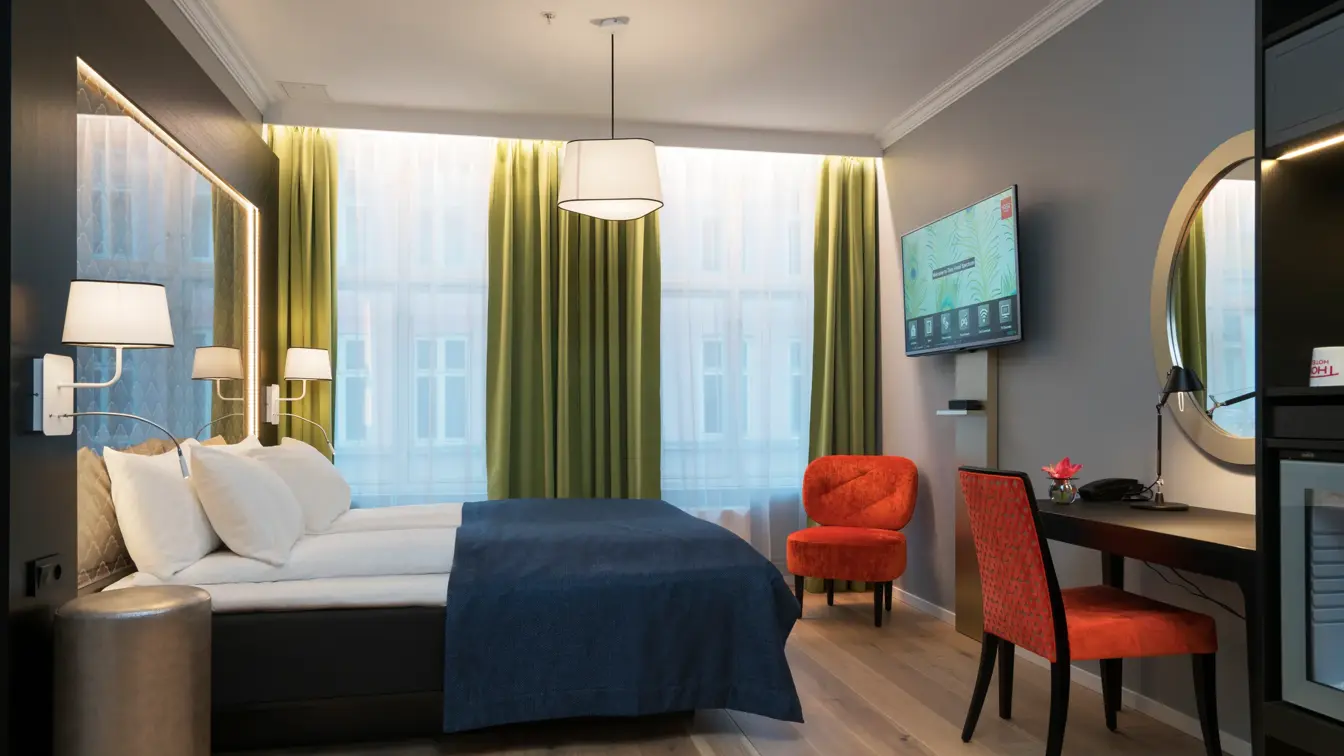 Dobbeltseng, skrivepult og sitteplass med mye gulvplasspå handikaprom på Thon Hotel Spectrum i Oslo sentrum