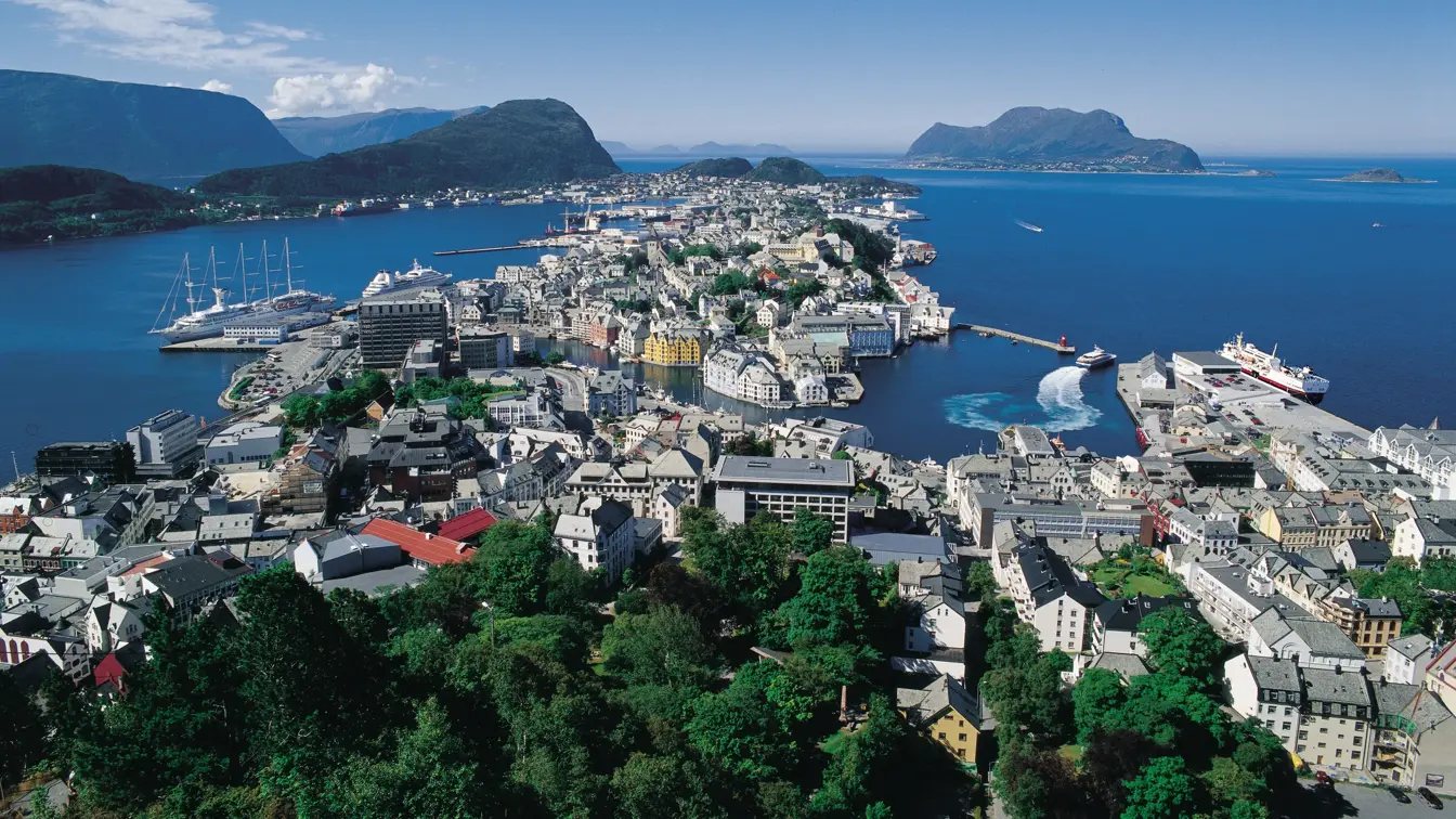 Utsikt over hele Ålesund by med fjord og fjell i bakgrunnen.