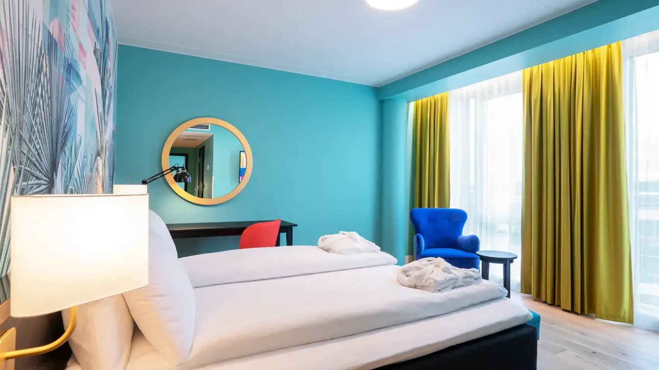 Fargerik palmetapet, dobbeltseng og stol i superior rom på thon Hotel Storo