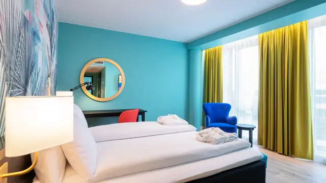 Fargerik palmetapet, dobbeltseng og stol i superior rom på thon Hotel Storo