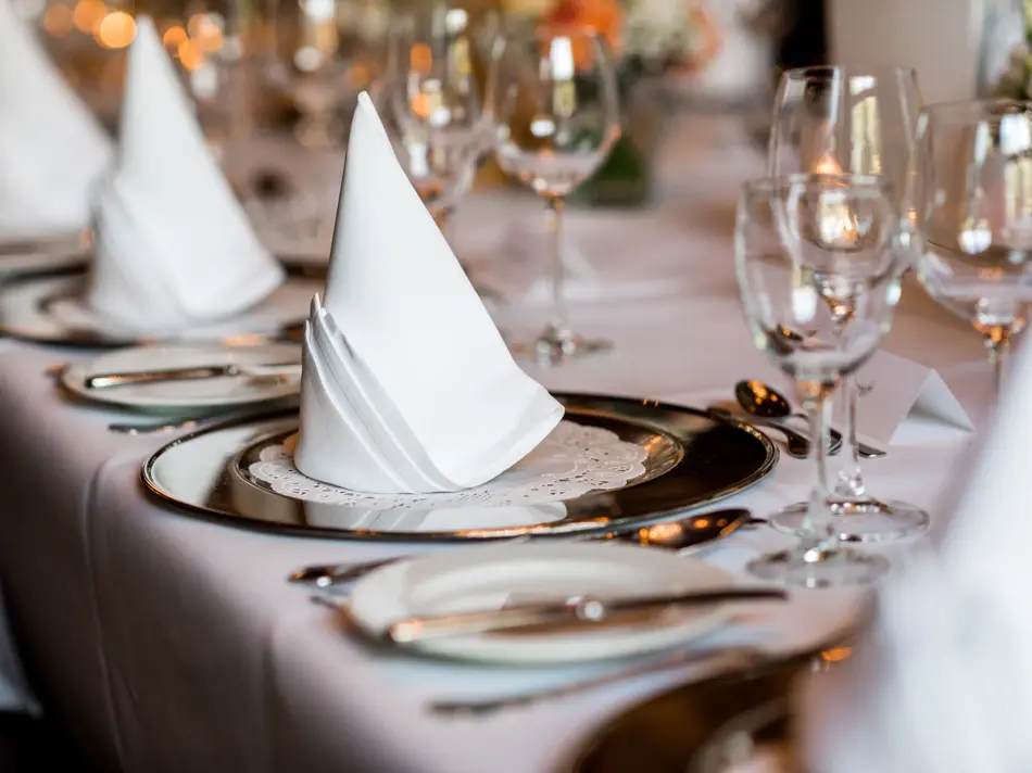 Bordsetting med hvit duk, hvite servietter og tomme vinglass