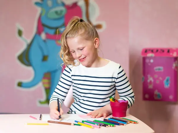 jente som sitter på rosa lekerom og fargelegger