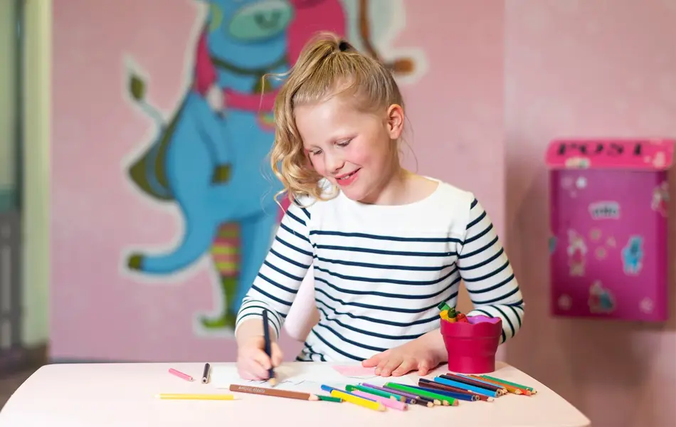 jente som sitter på rosa lekerom og fargelegger