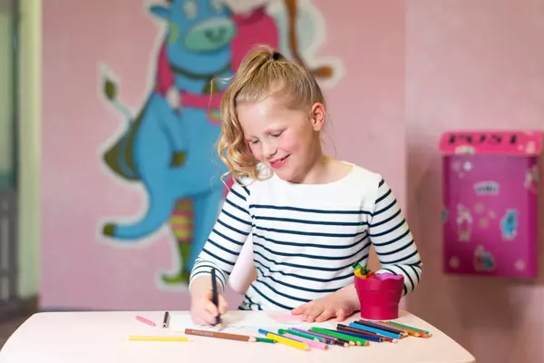 jente som sitter på rosa lekerom og fargelegger