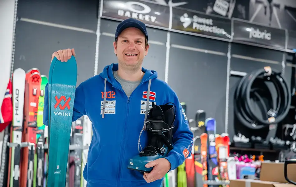 Butikkansatt som viser skiutstyr