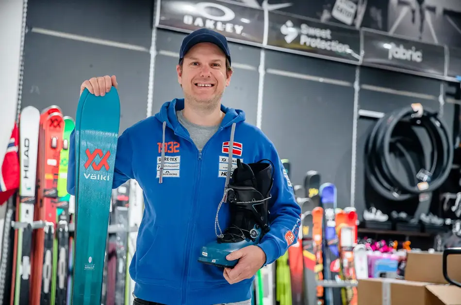 Butikkansatt som viser skiutstyr