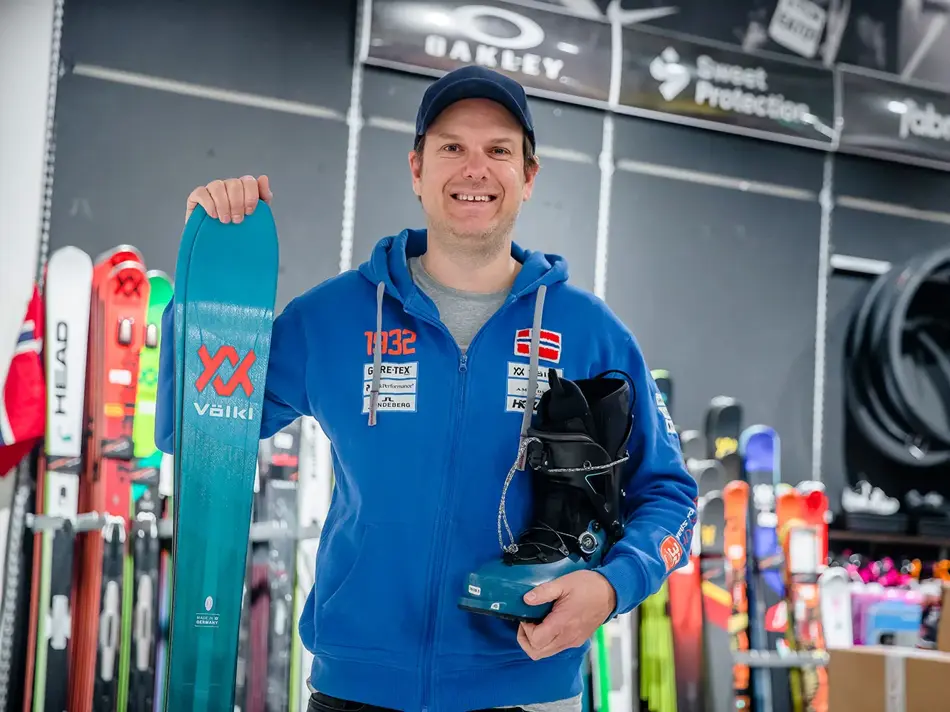 Butikkansatt som viser skiutstyr