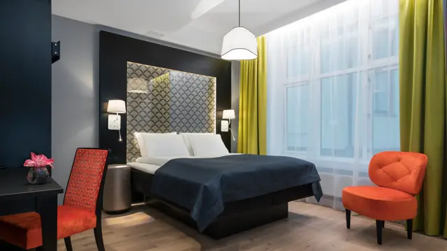 Dobbeltseng, skrivepult og sitteplass med mye gulvplasspå handikaprom på Thon Hotel Spectrum i Oslo sentrum