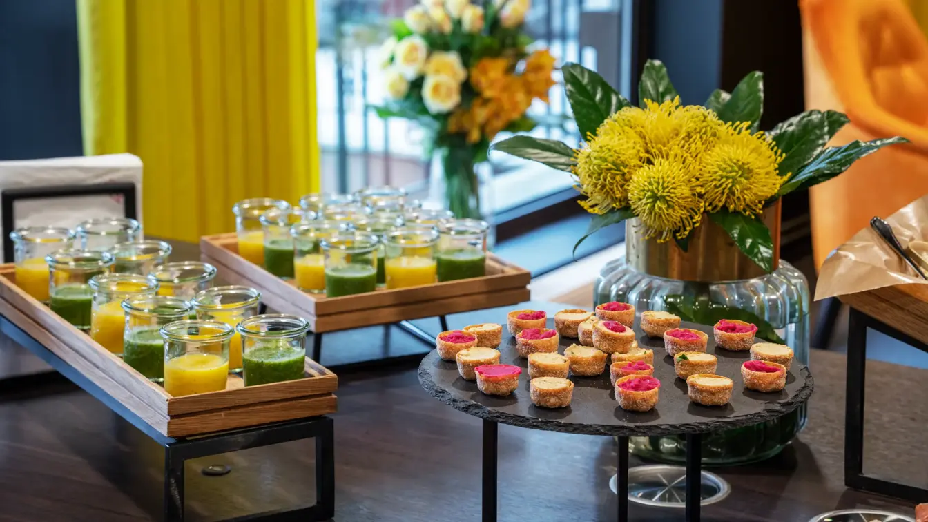 Smoothie, bakst, og blomster på et bord. 
