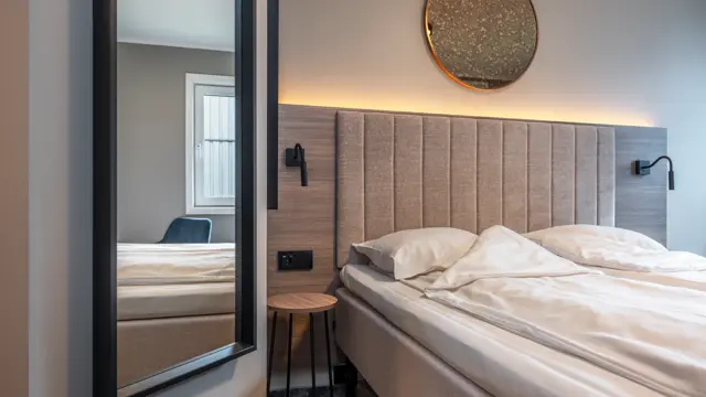 Dobbeltrom med queen seng, speil, sengegavl og nattbordslamper