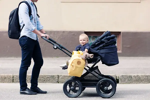 Bilde av mann som triller barn i barnevogn