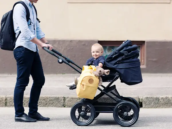 Bilde av mann som triller barn i barnevogn