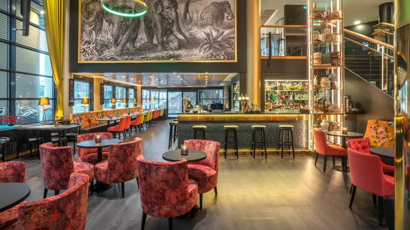 Bar, diverse sittegrupper, rosa stoler, svarte bord. 