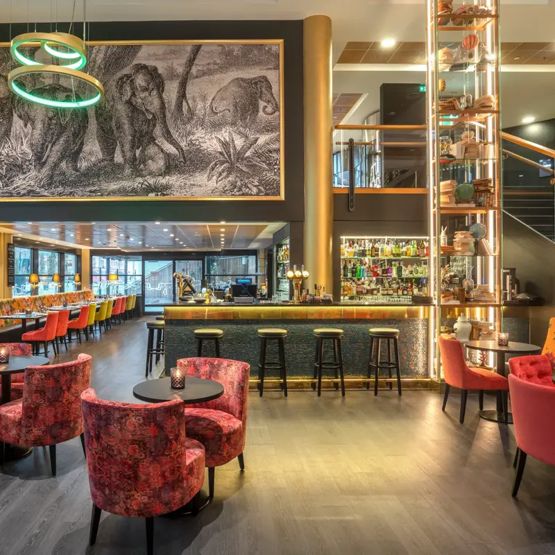 Bar, diverse sittegrupper, rosa stoler, svarte bord. 
