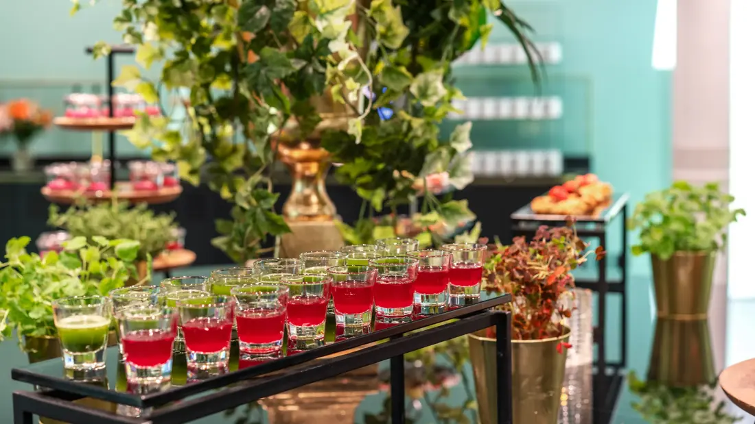 Pausebuffet med fargerike energishots, grønne planter og urter rundt.