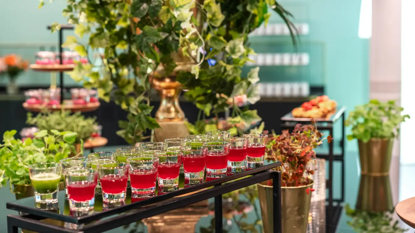 Pausebuffet med fargerike energishots, grønne planter og urter rundt.