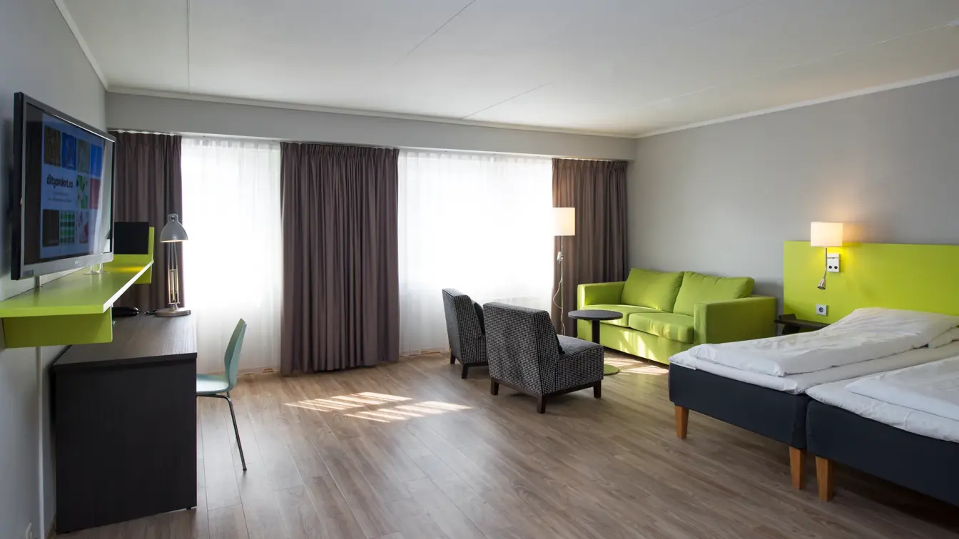 Seng, sittegruppe, skrivebord og TV i superior rom på Thon Hotel Hallingdal