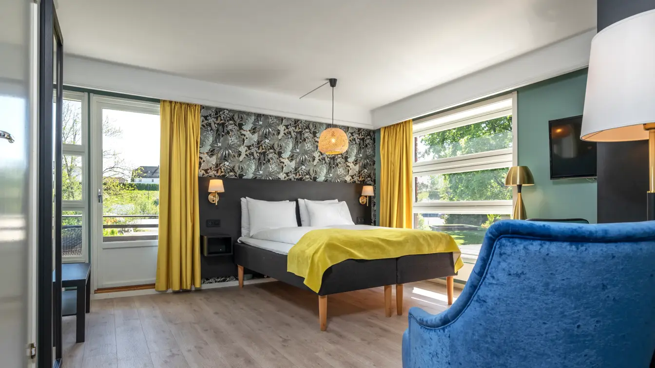 Familierom med dobbeltseng, store vinduer, gule gardiner og parkett