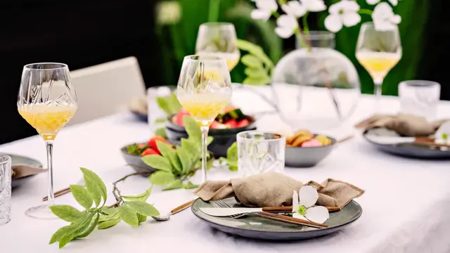 Bord dekket mørkt service og høye glass på en hvit duk 