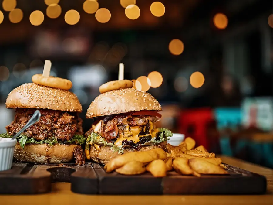 To trebrett med burger, fries, dip og løkring