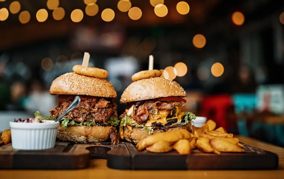 To trebrett med burger, fries, dip og løkring