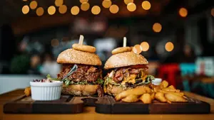 To trebrett med burger, fries, dip og løkring