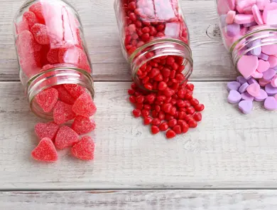 Canning jars laying on their sides filled with candy hearts and for Valentine's Day  on a rustic wood table.