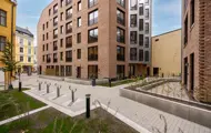 Felles uteområde mellom boligbygg med gangveier, sykkelstativer og grønne soner.