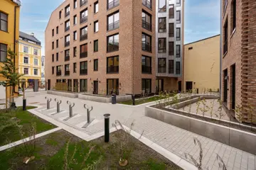 Felles uteområde mellom boligbygg med gangveier, sykkelstativer og grønne soner.