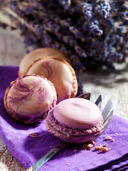 Macaron iauf lila Deckchen, Kuchengabel,  Lavendel, heller Holzuntergrund, Holztisch