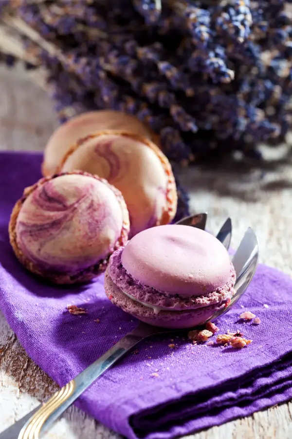 Macaron iauf lila Deckchen, Kuchengabel,  Lavendel, heller Holzuntergrund, Holztisch