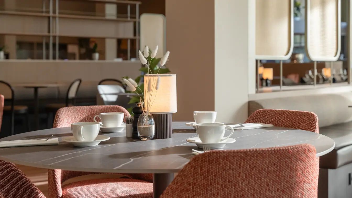 Rundt bord dekket med hvite kaffekopper og en liten bordlampe