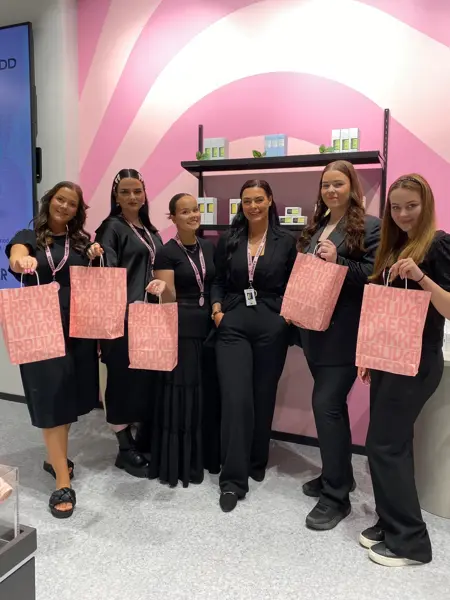 6 ansatte hos Blivakker viser fram rosa goodiebags