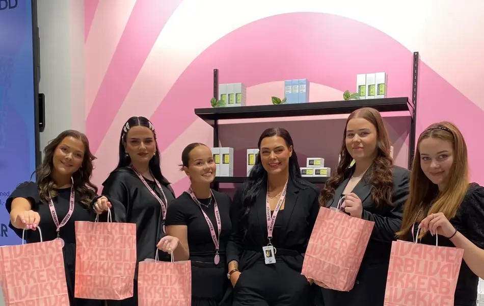 6 ansatte hos Blivakker viser fram rosa goodiebags