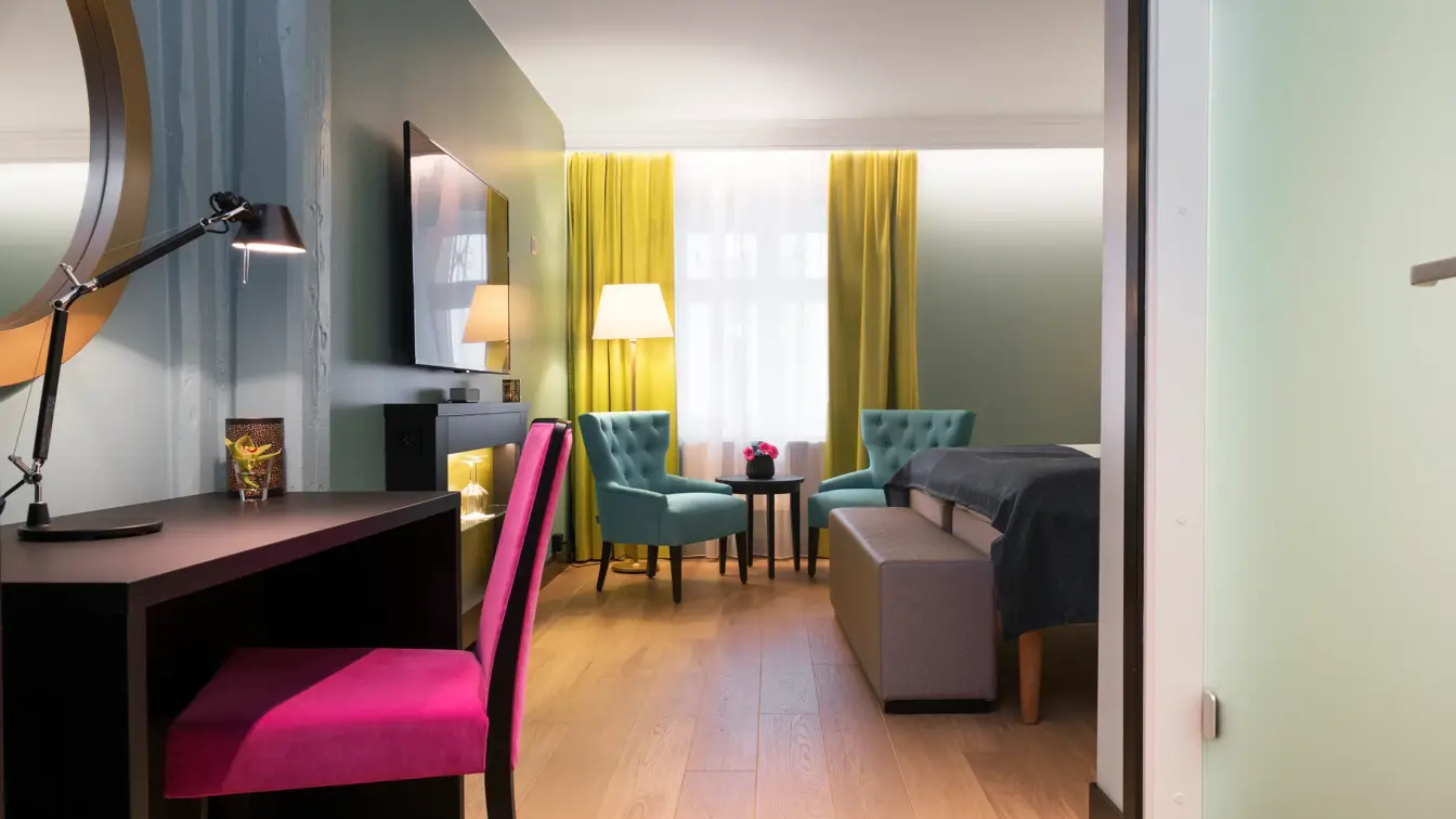 Skrivepult, sittegruppe, tv og gule gardiner på Thon hotel Terminus i Oslo sentrum nær Jernbanetorget