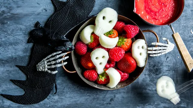 Fat med fruktfigurer som hodeskaller med halloweendekorasjon rundt