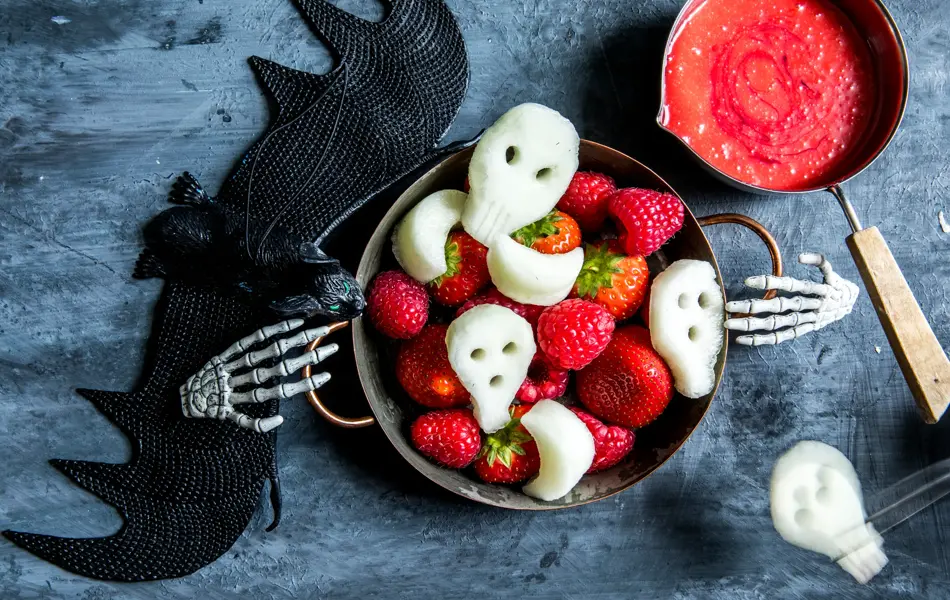 Fat med fruktfigurer som hodeskaller med halloweendekorasjon rundt