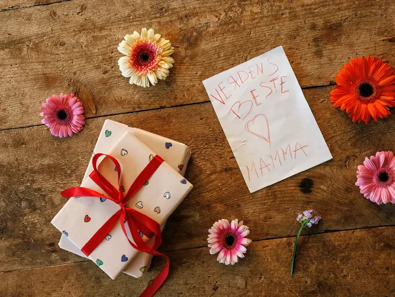 Blomster, gave og kort til mor på et bord