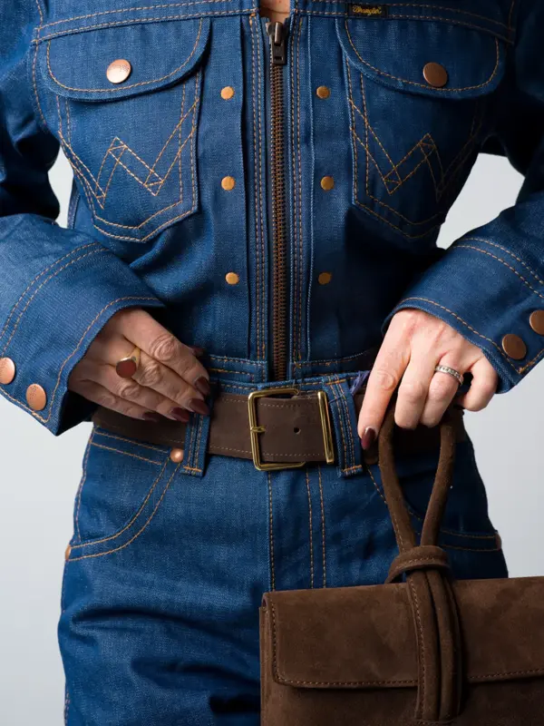 Marianne i jeansskjorte, jeans med brunt belte og brun veske.