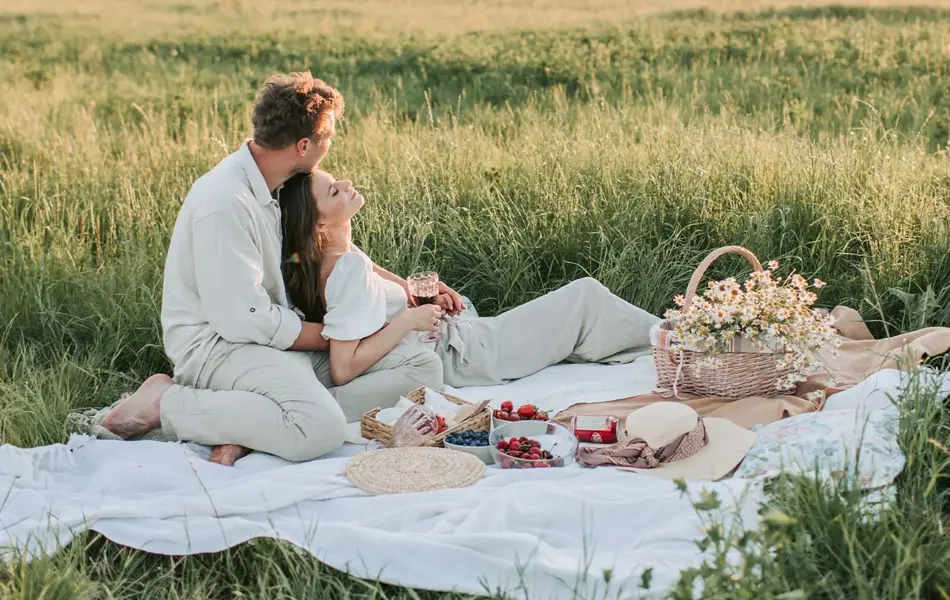 Dame og mann som har piknik i en eng