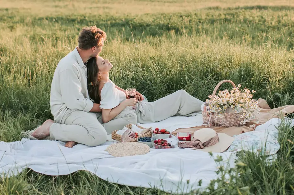 Dame og mann som har piknik i en eng