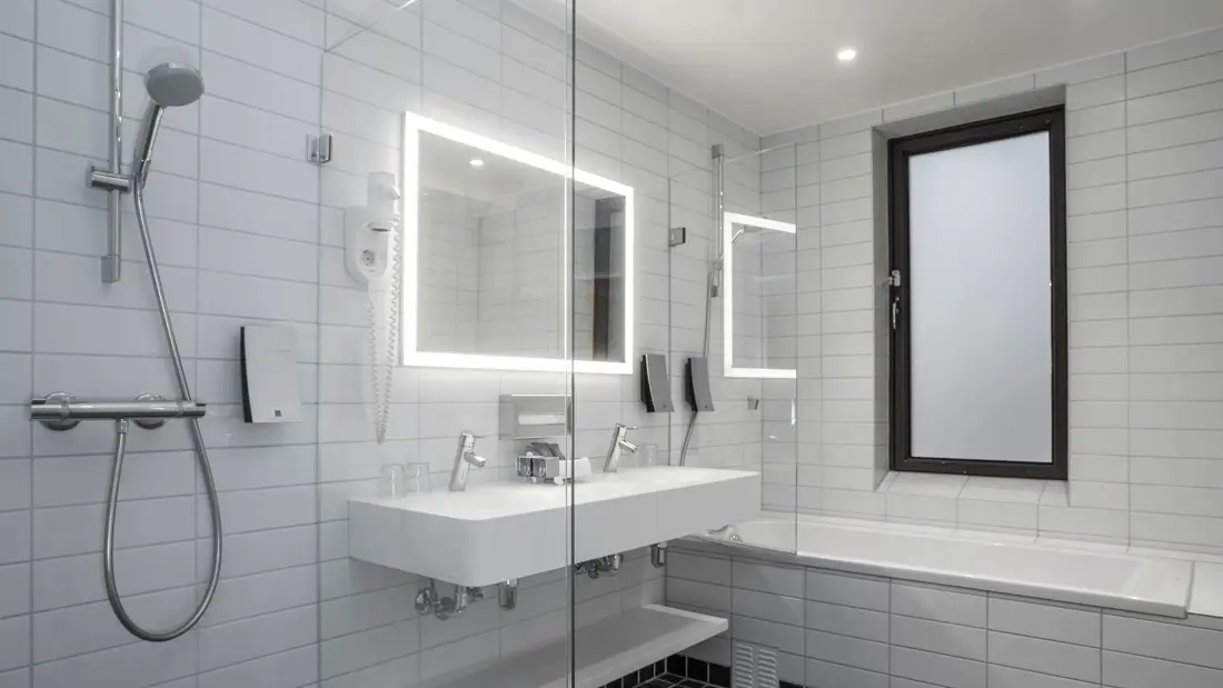 Svarte gulvfliser, hvite veggfliser, badekar, toalett,dusj, vask, speil. 