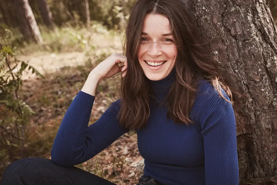 Brunette smiler til kamera iført genser i navy