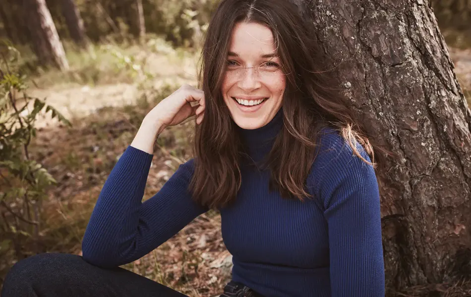Brunette smiler til kamera iført genser i navy