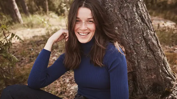 Brunette smiler til kamera iført genser i navy