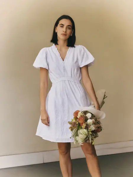 Dame som holder en blomsterbukett og har på seg en hvit kjole