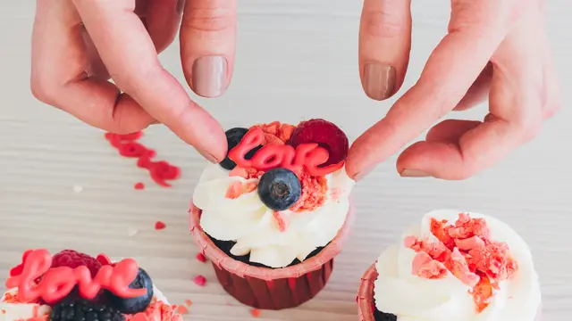 Sjokolademuffins med lys glasur dekorert med bær og spiselig love