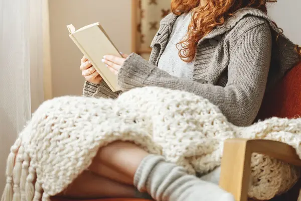 Happy young woman reading a book in a chair